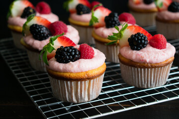 Lemon Cupcakes with Lemon Raspberry Buttercream Icing: Cupcakes decorated with pink frosting and fresh berries on wire cooling racks