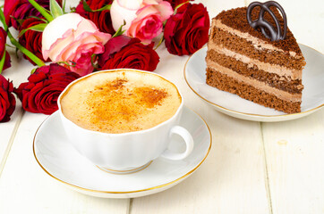 Piece of chocolate cake, cappuccino, flowers on table