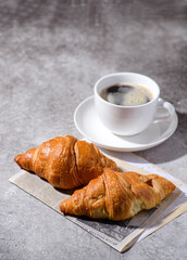 croissants on a gray background and a cup of coffee