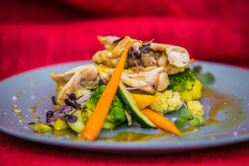 Chicken thigh on roasted vegetables on plate. The food in the restaurant. Food styling and restaurant meal serving.