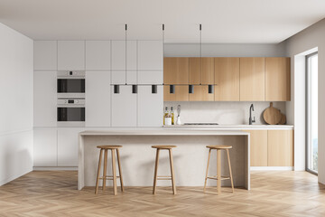 Modern kitchen interior with white walls, a wooden parquet floor and white countertops. A long...