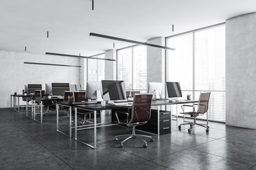 Light grey office room with armchairs and computers on the tables near window