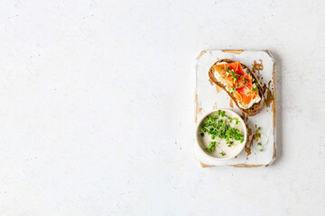 Toasted bread with ricotta (cream cheese), smoked salmon and micro greens served on wooden rustic board. Health care, super food concept. White Stone background. Top view. Copy space.