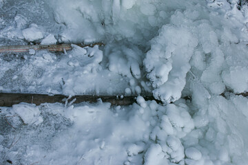 Winter. Everything is covered with snow. Leak in the connection of pipes pumping water out of the...