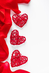 Frame of silk red ribbon and hearts on a white background