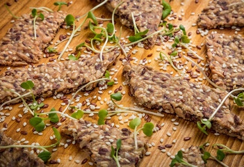 Crunchy crispy seed homemade bread decorated with microgreen sprouts on a wooden table. Healthy snack. multigrain cereal flax, sesame and sunflower seeds. Close up flat lay view