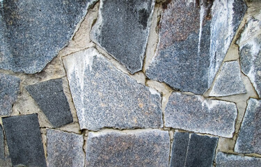 Large granite stones embedded in the wall. Stock photo with coated solid surface.