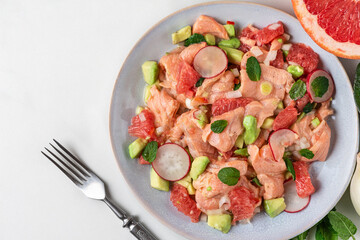 Chilean salmon seviche with grapefruit, avocado, radish, onion and mint in a plate with fork. Healthy diet food. top view