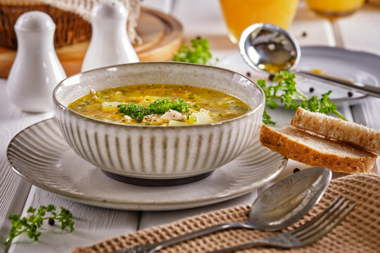 Chicken soup with crispy bread and orange juice on a white wooden table close-up