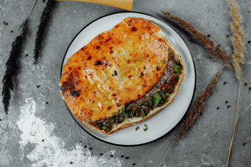 Top view on georgian khachapuri with lamb and chili peppers on the wooden table