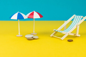 Beach relaxation and vacation concept. Toy sun lounger and umbrella on colorful paper background.
