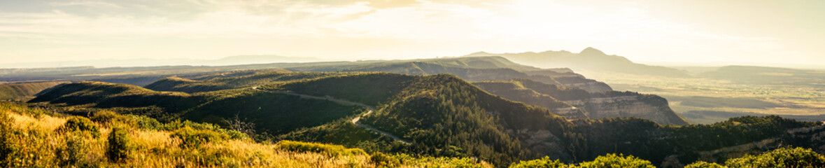 Fototapeta na wymiar Panorama shot of cliffs road goes to mesa verde national park in haze at sunny day in america