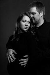 Young couple embrace tenderly and sensually. Black and white photo. Vertical. Pregnant woman with her husband.