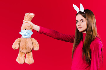 Serious brunette young woman looking to the camera. Beautiful girl holding Easter bunny ears, plush...