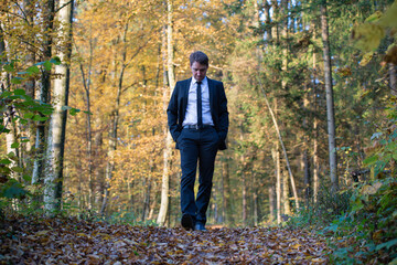 Fototapeta premium Businessman in a suit walking in forest