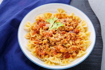 Pasta in tomato bolognese sauce on a round black stand on a blue napkin