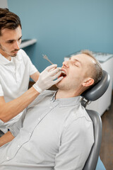Dentist adjusting dental braces during orthodontic treatment for the young male patient. High quality photo