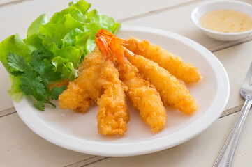 Fried shrimps with green vegetable on plate and dip sauce .