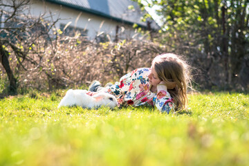 child and rabbit lying togeter in green grass in spring time
