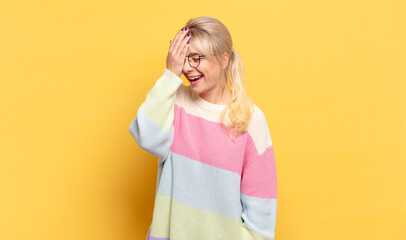 blonde woman laughing and slapping forehead like saying d’oh! I forgot or that was a stupid...