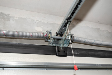 Springs tensioning the home garage door mechanism, view from the inside, visible rail with chain.