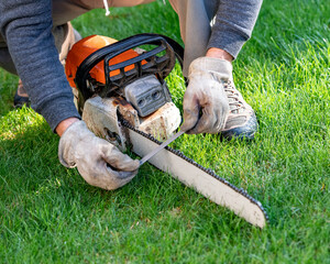Lumberjack sharpens a chainsaw with a file