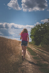 Naklejka premium girl walking alone in magic summer afternoon in golden hour time