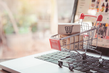 Shopping online. cardboard box with a shopping cart logo in a trolley on laptop keyboard. Shopping...