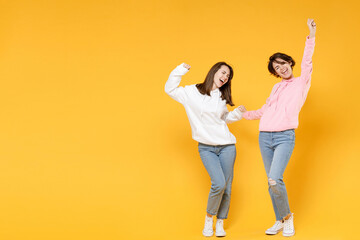 Full length of happy two young women friends 20s wearing basic white pink hoodies doing winner...