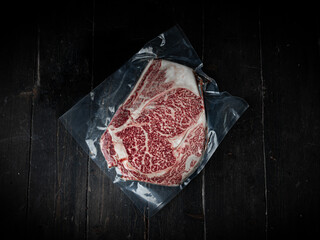 Vacuum-packed piece of Wagyu beef steak. Raw beef steak on a wooden background in a butcher shop....