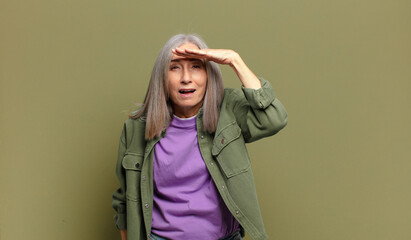 senior woman looking bewildered and astonished, with hand over forehead looking far away, watching...