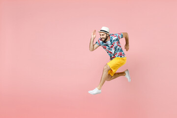 Fototapeta na wymiar Full length side view of cheerful young traveler tourist man in summer clothes hat jumping like running isolated on pink background. Passenger traveling abroad on weekend. Air flight journey concept.