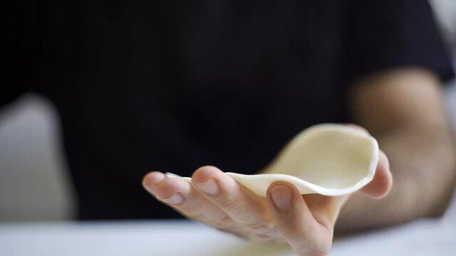 Close-up of male hands preparing a traditional argentinean empanada. Filling the dough and closing it with a hand made repulgue. 