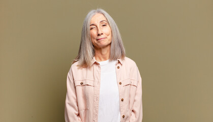 senior woman looking happy and friendly, smiling and winking an eye at you with a positive attitude