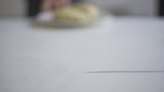Hand delivering 2 Empanadas served on a white plate.