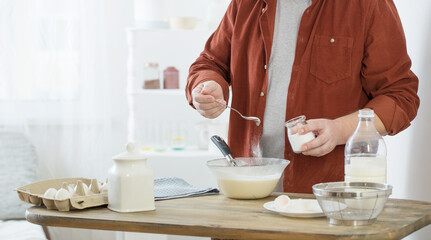 middle-aged man kneading pancake dough on white kitchen