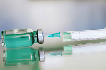 Vial filled with liquid vaccine in medical lab with syringe. medical ampoule and syringe on the glass surface