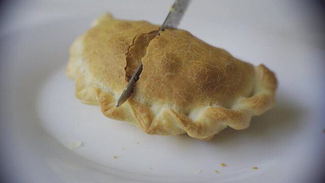 Close up of a knife cutting a recently baked warm empanada. Argentina