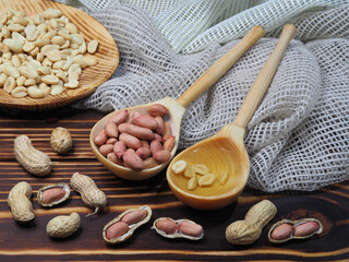 Peeled peanuts, in shell nuts, peanut oil in a wooden spoon, salted peanuts in a plate on a wooden background, closeup, top view. Natural ground nuts arachis hypogaea for a healthy diet