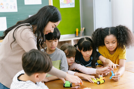 Group of Diverse Elementary School Pupils and Female Asian teacher demonstrating making electric remote control car in science lesson. Education, elementary school, learning, science workshop concept.