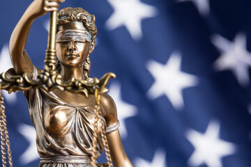 The statue of justice Themis or Justitia, the blindfolded goddess of justice against the flag of...
