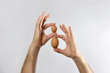 Two chicken eggs of different sizes are held in the hands of a man.The concept of size...