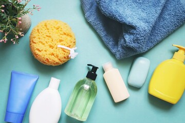 Obraz na płótnie Canvas Bath products gift set top view photography. Different types shampoo, hair balm, conditioner, face cream, soap supplies, yellow sponge and blue towel