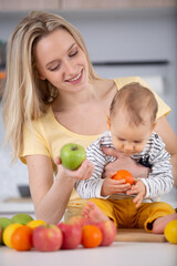 Fototapeta na wymiar woman and baby in the kitchen making healthy fruit salad