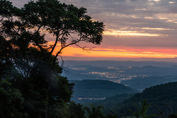 Sunset with trees, forest, valley and city lights