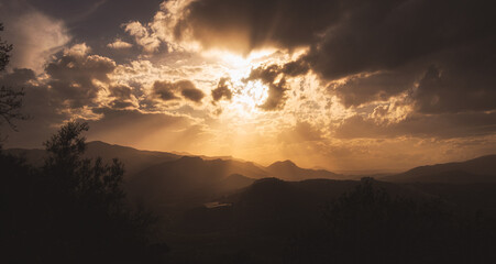 landscape at sunset, with a cloudy sky and sun rays through the clouds.