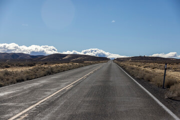 Road runs through empty desert and sagebrush heading toward the mountains