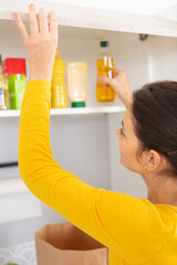 attractive young woman is opening shelf in kitchen