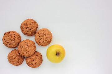 Homemade oatmeal cookies and golden apple on white table. Overhead view of oat biscuits and fresh fruits on white background with copy space