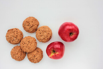 Homemade oatmeal cookies and red apple on white table. Overhead view of oat biscuits and fresh fruits on white background with copy space